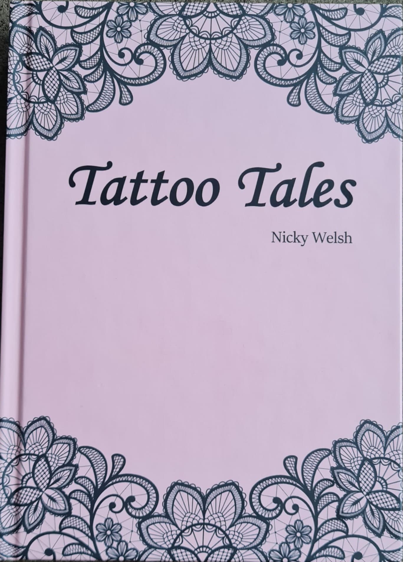 Front cover of “Tattoo Tales” by Nicky Welsh, pink with a lace border