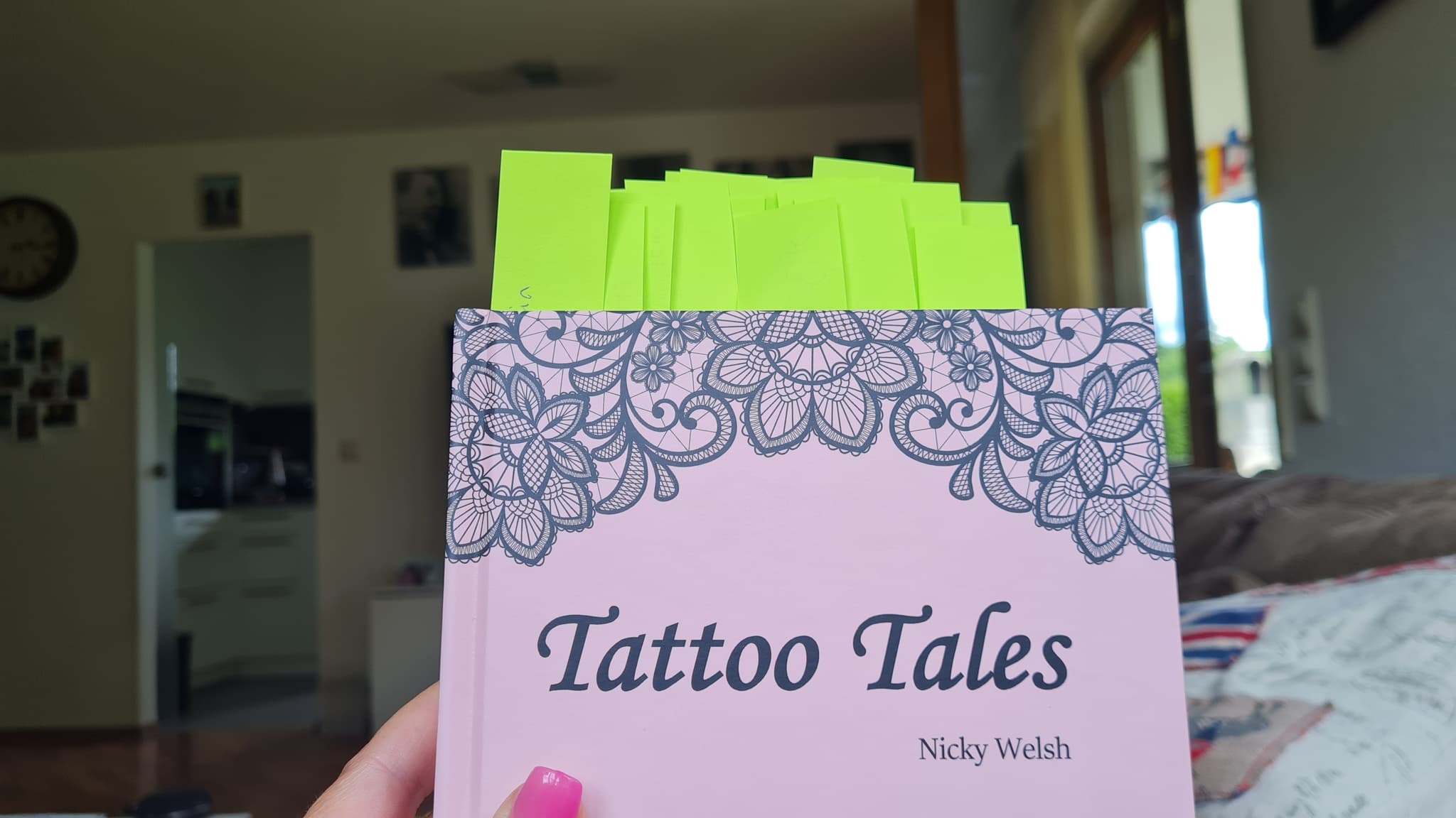 The book on a table, its pages marked with green sticky notes