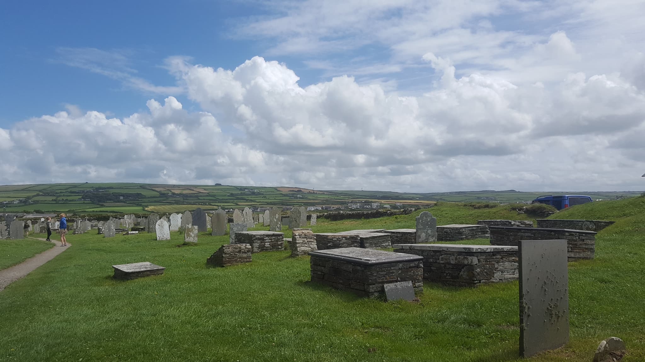 Flat tombstones under a wide, cloudy sky in a coastal graveyard
