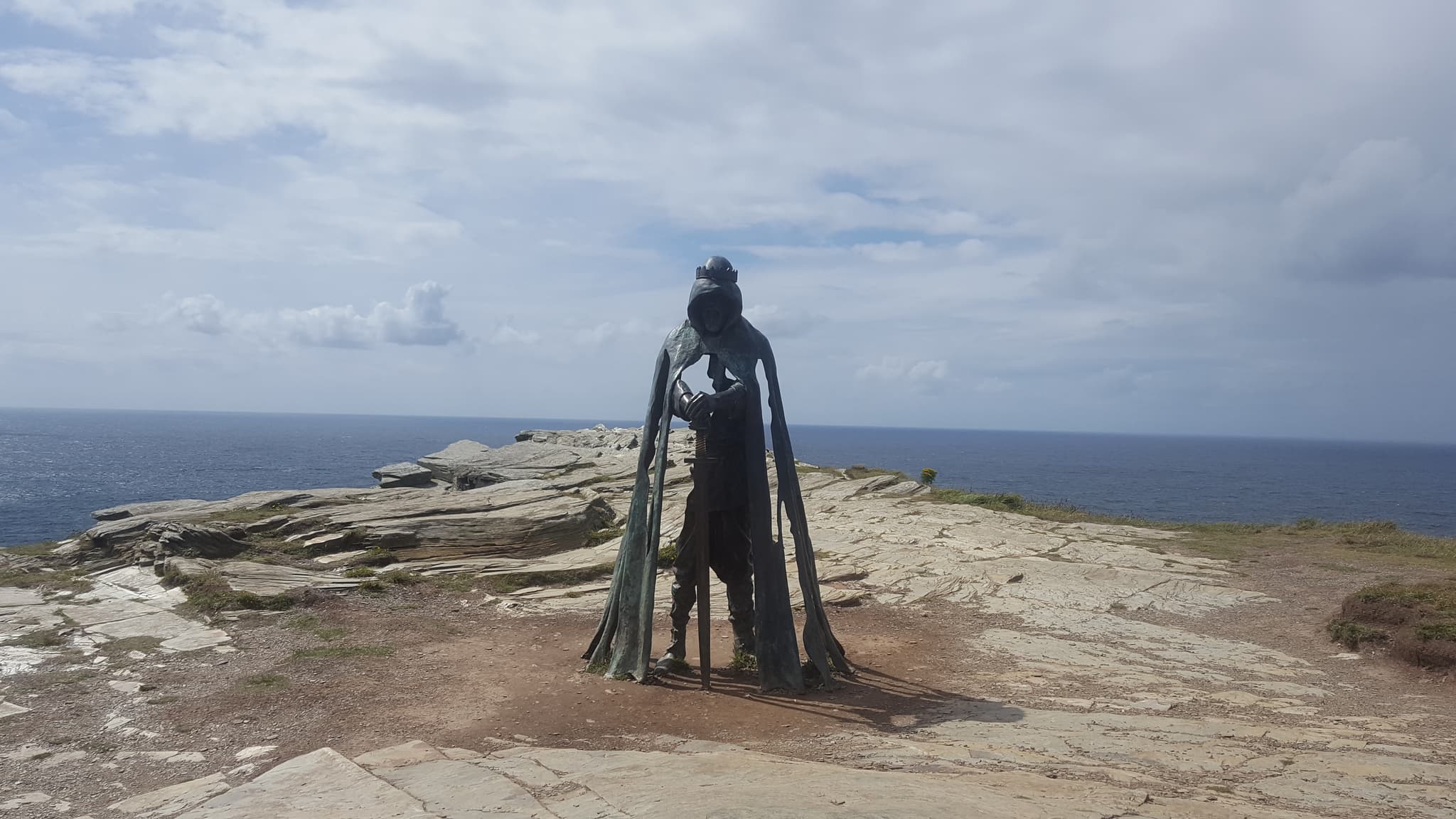Eine dunkle Bronzefigur eines Ritters auf einer Klippe